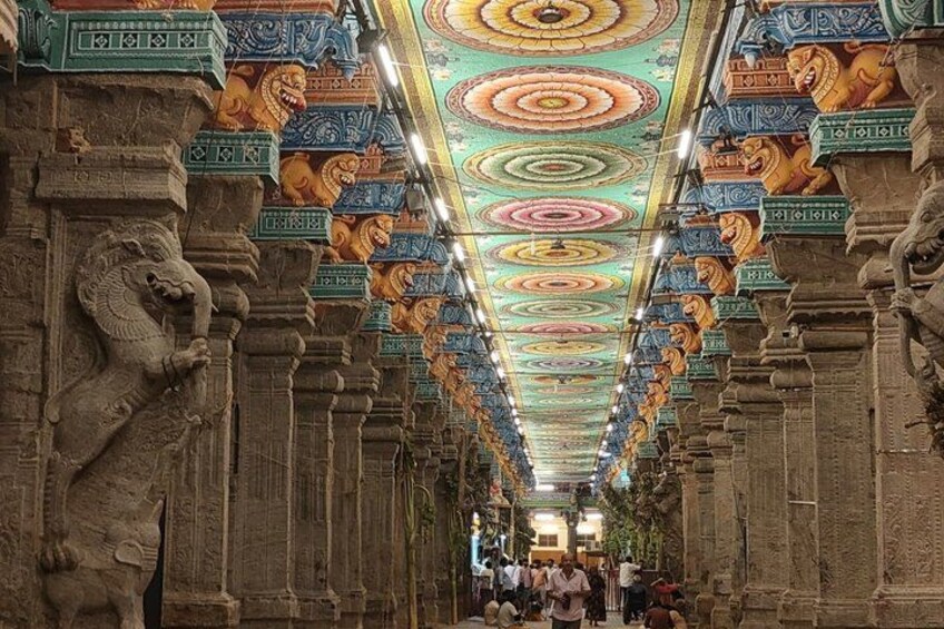 A temple corridor with ornate columns and a colorful ceiling. 3