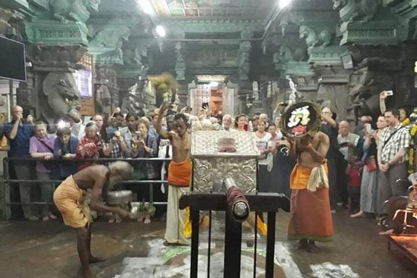 A temple interior with a crowd, a central altar, and a statue. 3