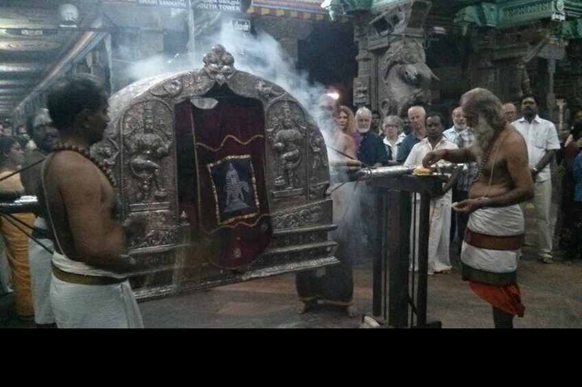 A religious ceremony with a decorated altar, a priest performing rituals, and a crowd observing. 4
