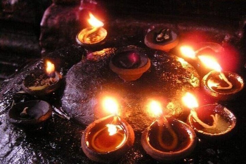A collection of lit oil lamps on a textured surface. 5