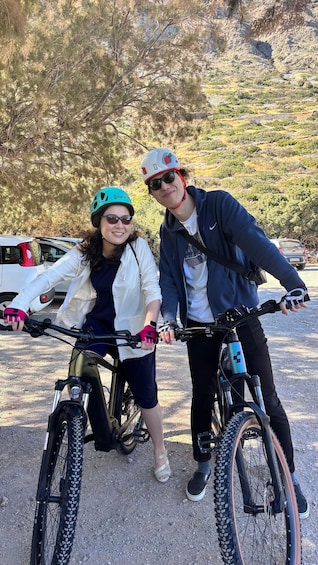 Two people on bicycles in a parking lot with a hilly landscape in the background. 3