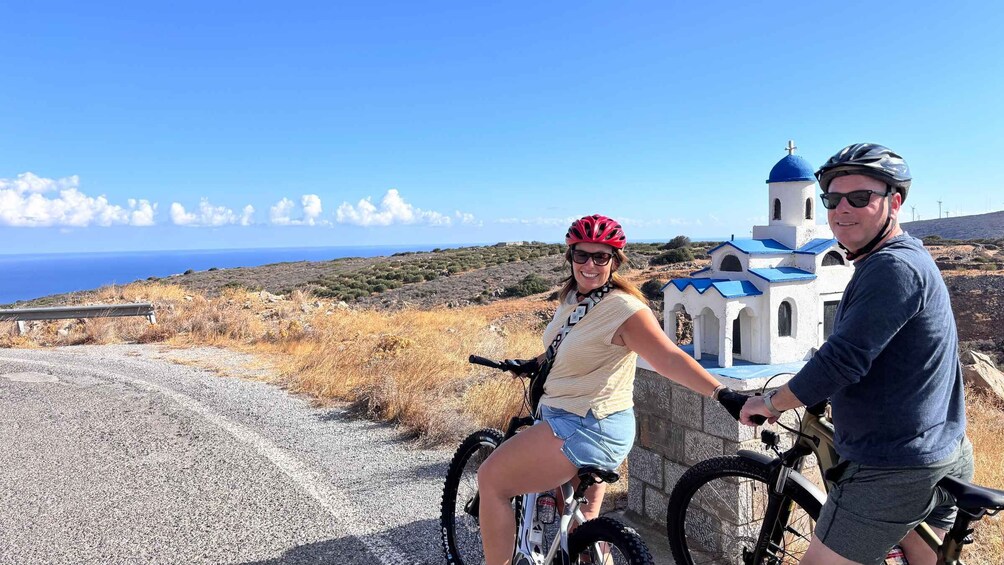 Two people on bicycles, a church, and a coastal landscape. 1