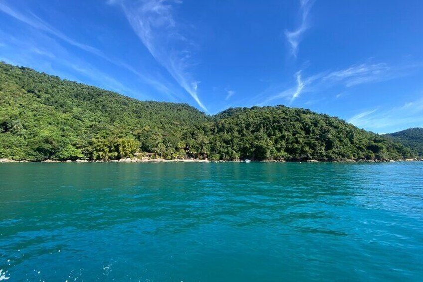 A clear blue sea, a green forested hill, and a clear sky. 4