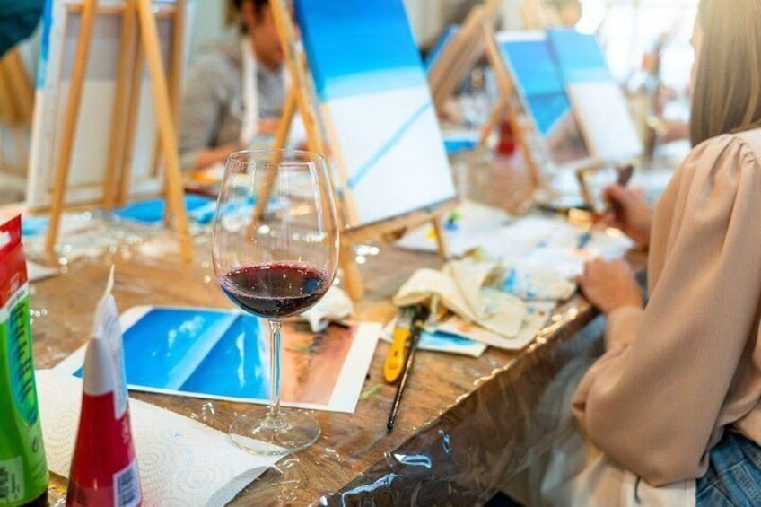 A glass of red wine on a table with art supplies and canvases in an art studio. 2