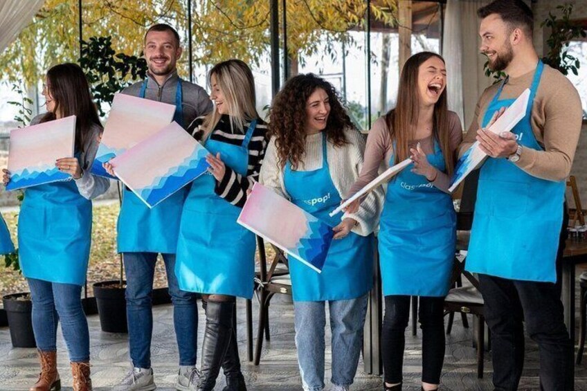 A group of people in aprons holding painted canvases. 4