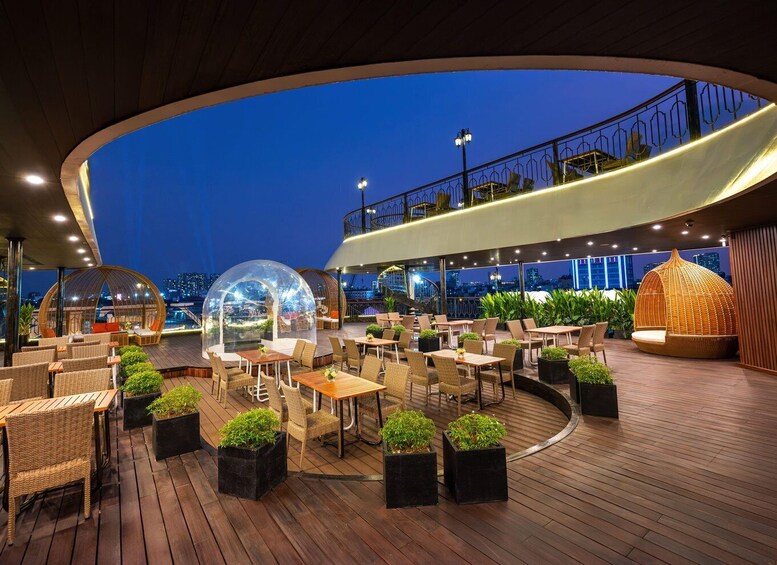 An outdoor dining area with round tables, chairs, and planters. 4