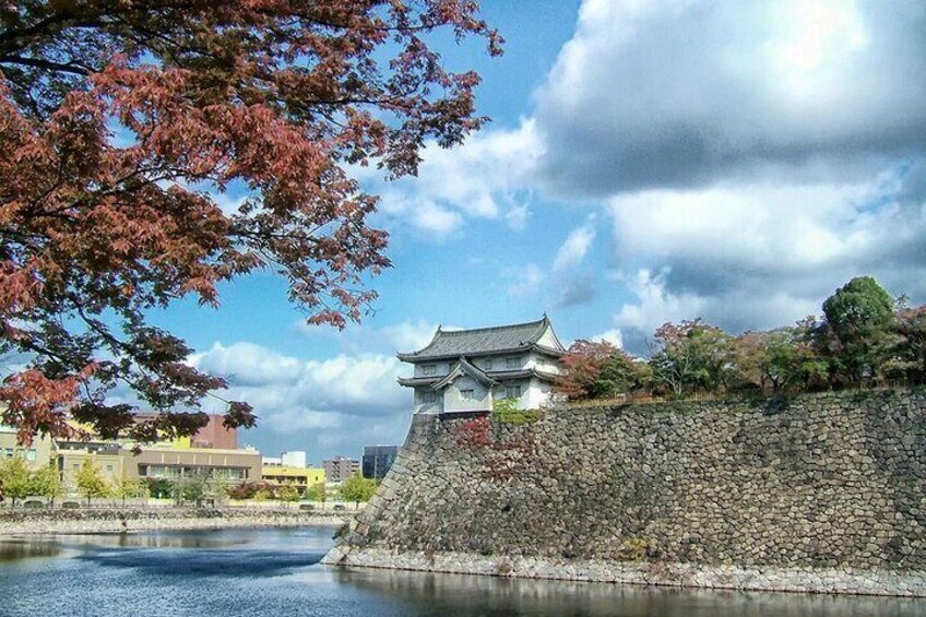 A traditional Japanese building by a stone wall and water. 4