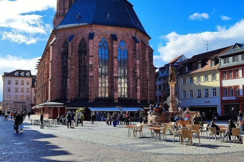A historic church with a prominent dome and large windows, surrounded by cobblestone streets and cafes. 1