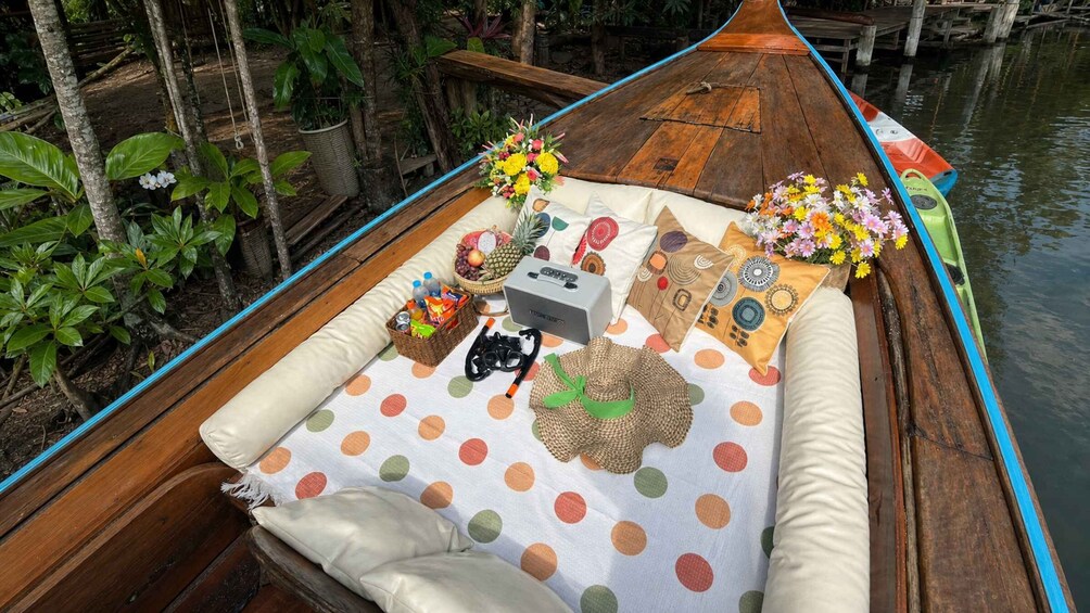 A boat with a polka dot mat, pillows, a radio, and flowers. 4