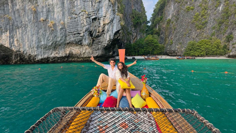 A couple on a boat with a rocky cliff and clear water in the background. 1