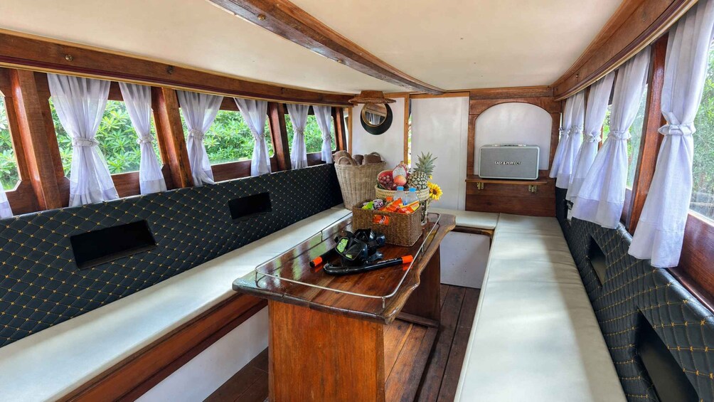A boat interior with a dining area, wooden walls, and a window with curtains. 3