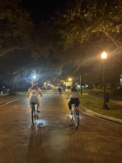 A nighttime scene with cyclists on a paved path, illuminated by street lamps. 3
