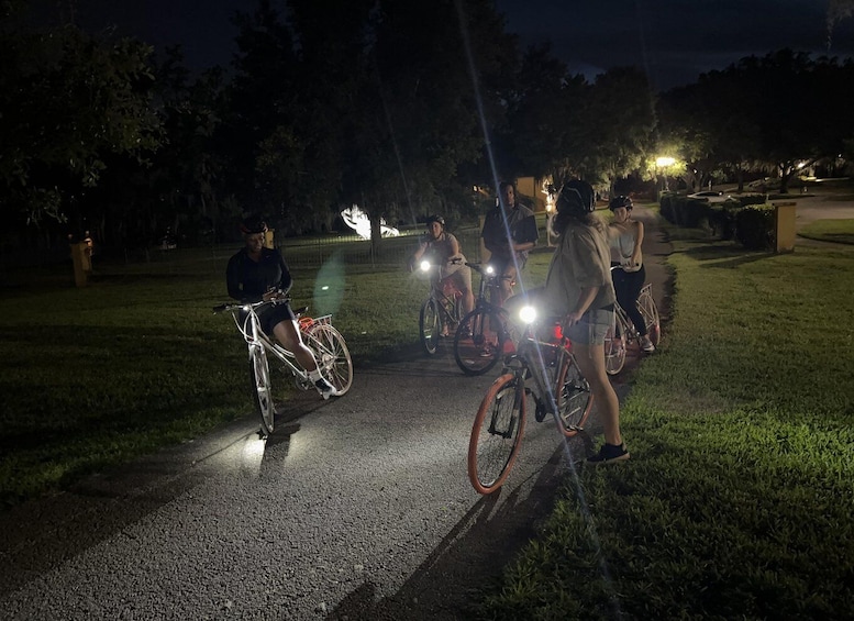 A group of cyclists on a paved path at night with headlight illumination. 4