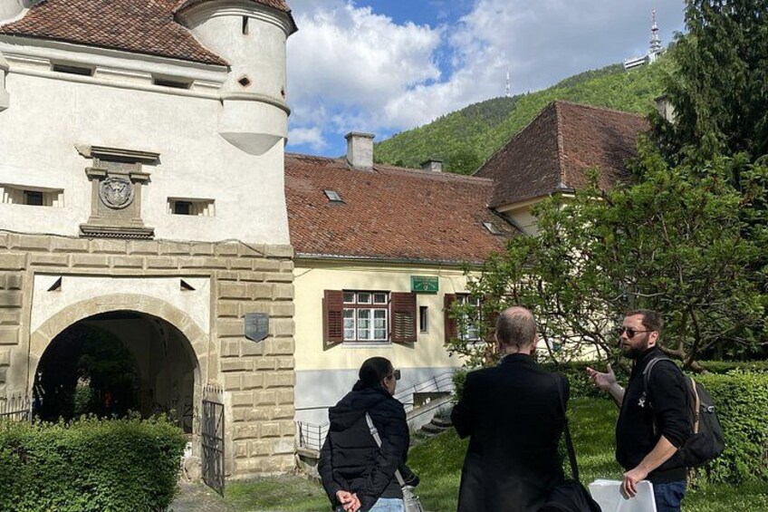 A historic building with a tower, a stone archway, and a green hill in the background. 3
