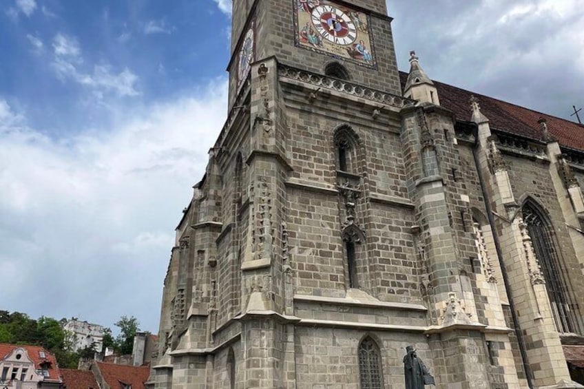 A historic stone church with a clock tower, arched windows, and a statue. 4