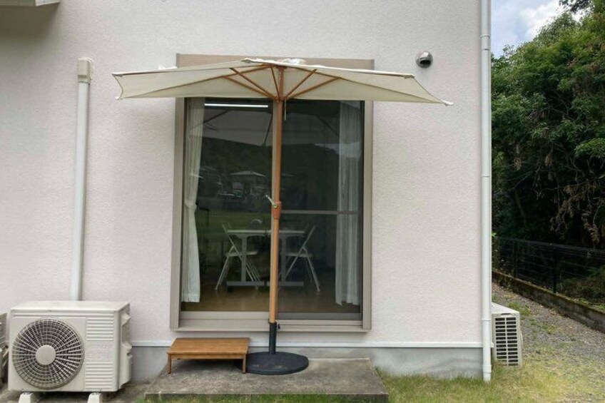A house with a sliding glass door, a standing fan, and a wooden bench outside. 2
