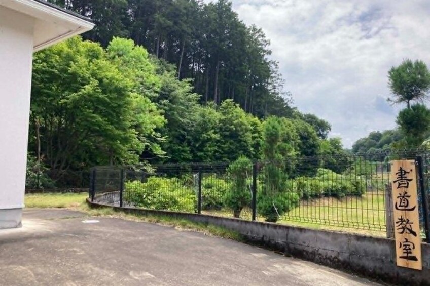 A fenced area with a sign, trees, and a building. 5