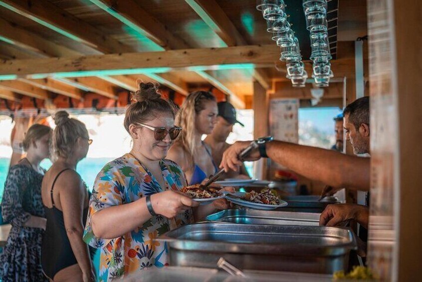 People serving themselves food at a buffet with metal serving trays. 4