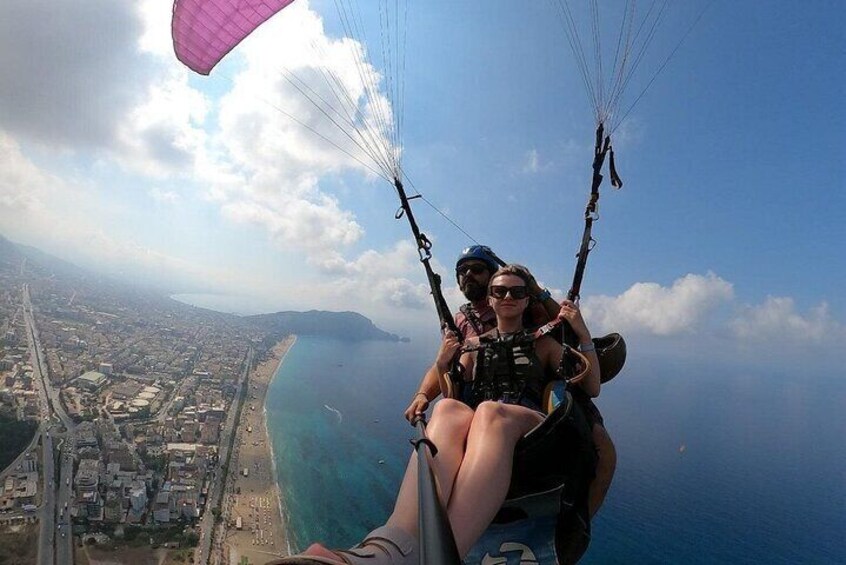 A person paragliding over a coastal city with a clear view of the coastline and urban landscape below. 5