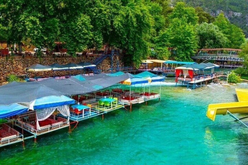A floating dock with canopies, a clear turquoise sea, and lush greenery in the background. 5