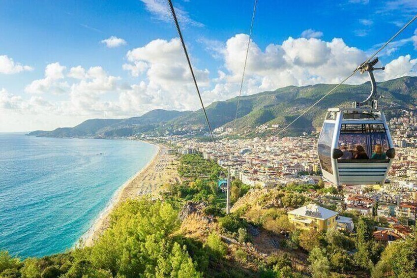 A cable car over a coastal city with a beach and mountains in the background. 4