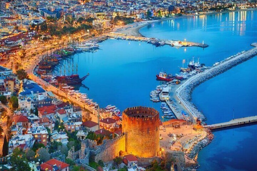 A coastal cityscape with a prominent castle, a marina, and a curved harbor. 2
