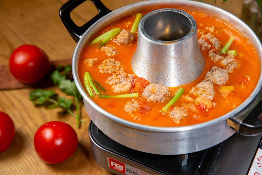 A pot of soup with meatballs and green vegetables on a stove. 5