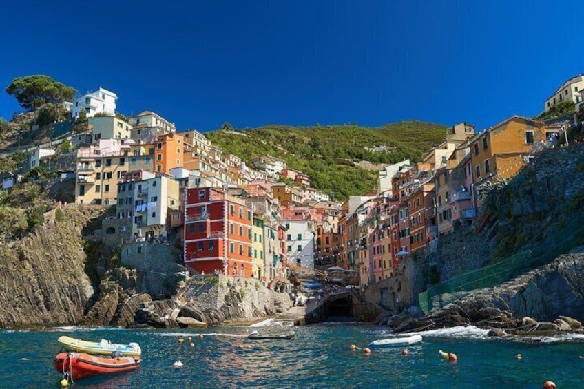 Colorful buildings on a hillside by the sea, a red boat, and swimmers in the water. 5