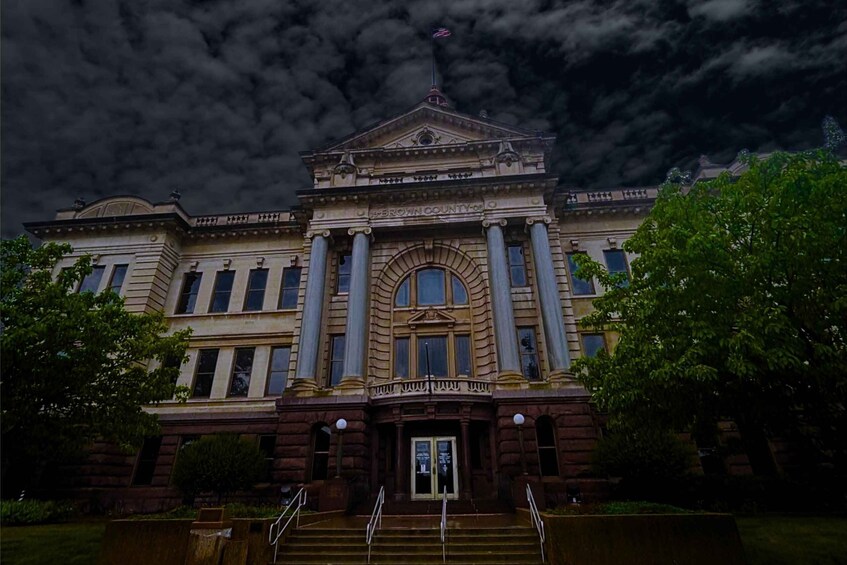 A stately building with columns, a central arch, and a flag atop. 3