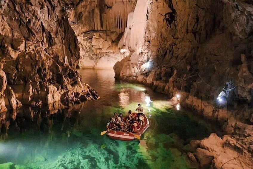 A group of people in a boat navigating a narrow, rocky waterway within a cave. 1