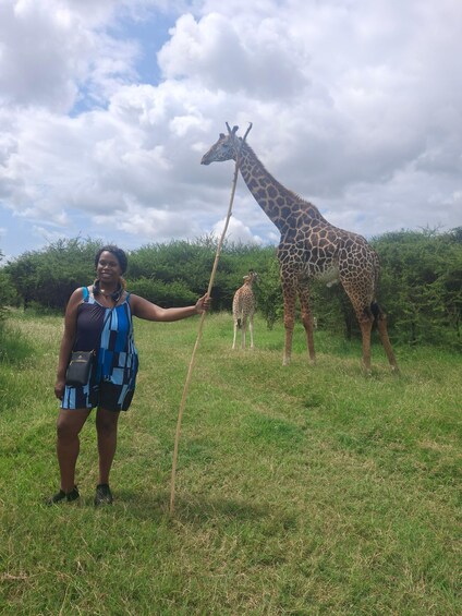 A person standing in a grassy field with giraffes in the background. 3