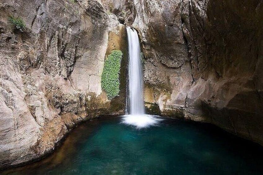 A waterfall in a rocky cave with clear water. 1