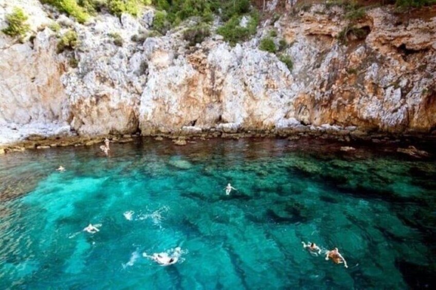 Une mer d’un bleu profond où l’on peut nager, avec des falaises rocheuses en arrière-plan. 2