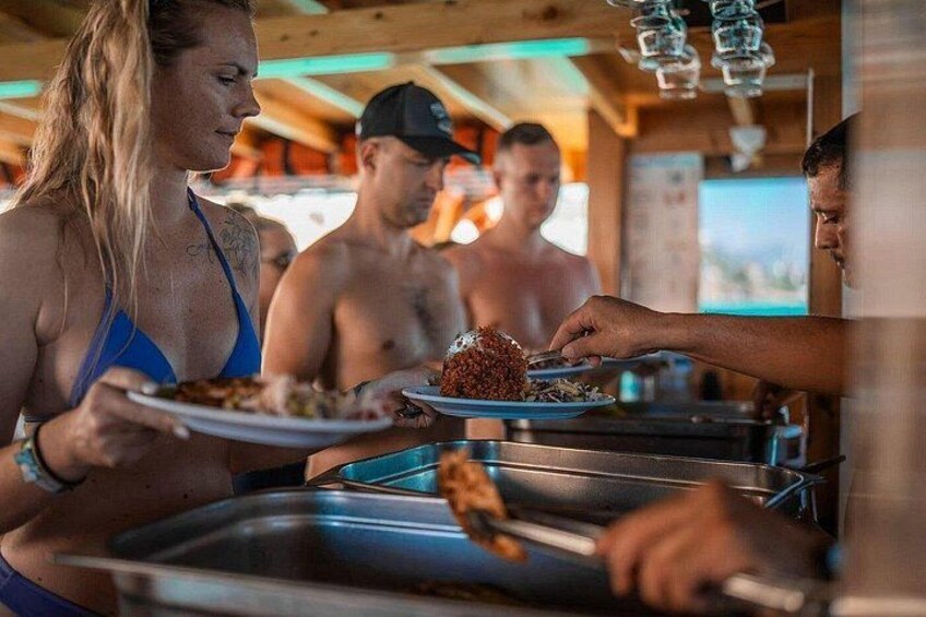 People dining at an outdoor buffet with a wooden structure overhead. 5