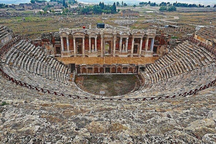 An ancient amphitheater with a central stage and tiered seating. 3