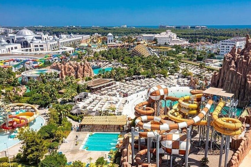 A water park with multiple slides and pools, surrounded by palm trees and a mountainous landscape. 4