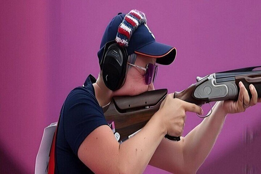 A person aiming a shotgun with a pink background. 3