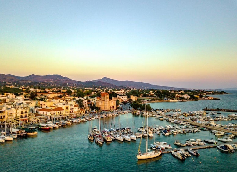 A coastal town with a marina filled with boats, a prominent church, and mountains in the background. 2