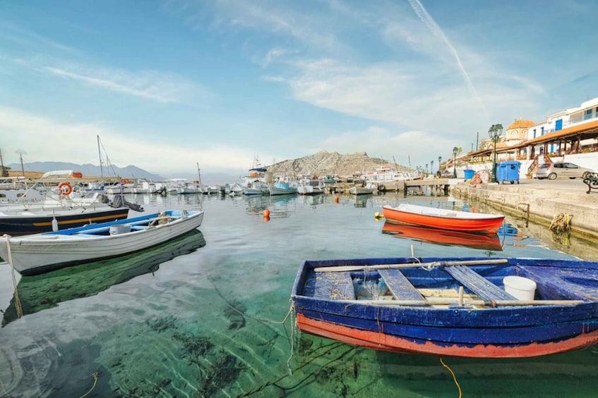 A marina with various boats docked, clear water, and a rocky hill in the background. 5