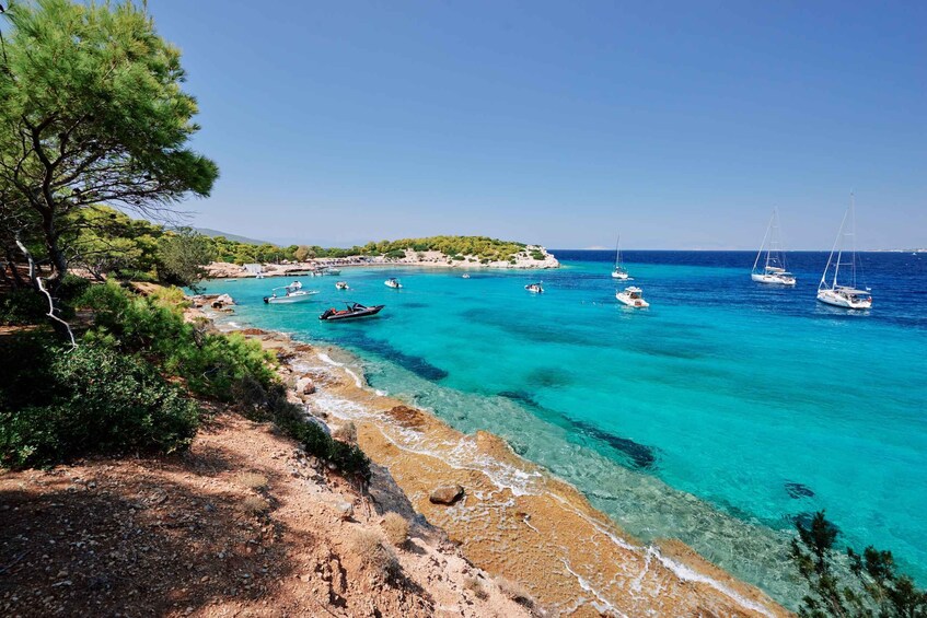 A coastal landscape with clear turquoise waters, boats, and a tree-lined shore. 4