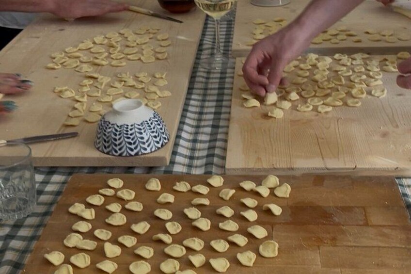 A person preparing food on a wooden table with dough and a patterned bowl. 5