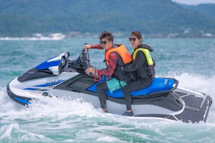 Two people on a jet ski with life jackets, water splashing around them. 3