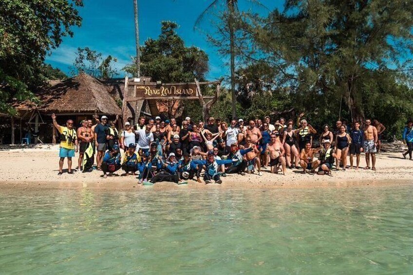 A group of people on a beach with a sign that reads 'Ring Reef Island.' 2