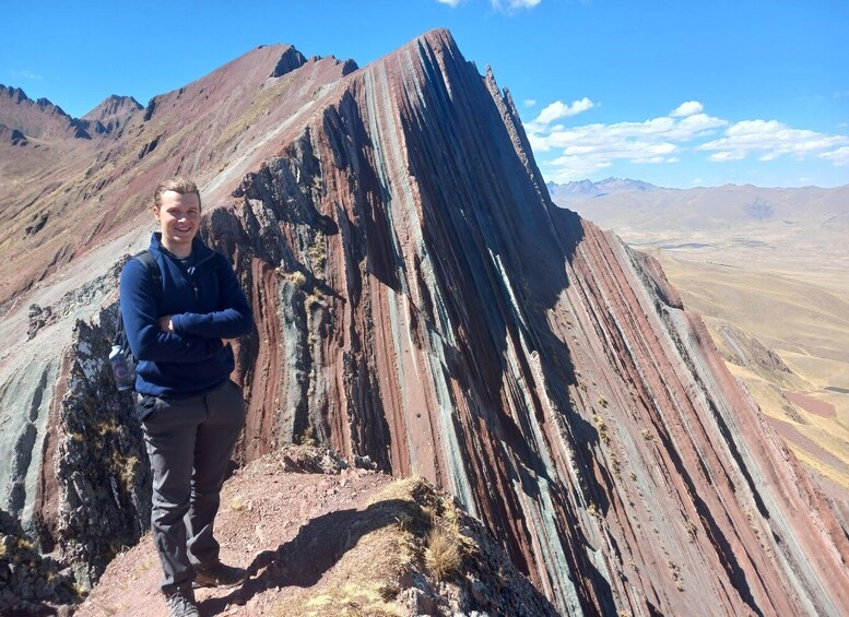 A person standing on a rocky outcrop with a mountain range in the background. 4
