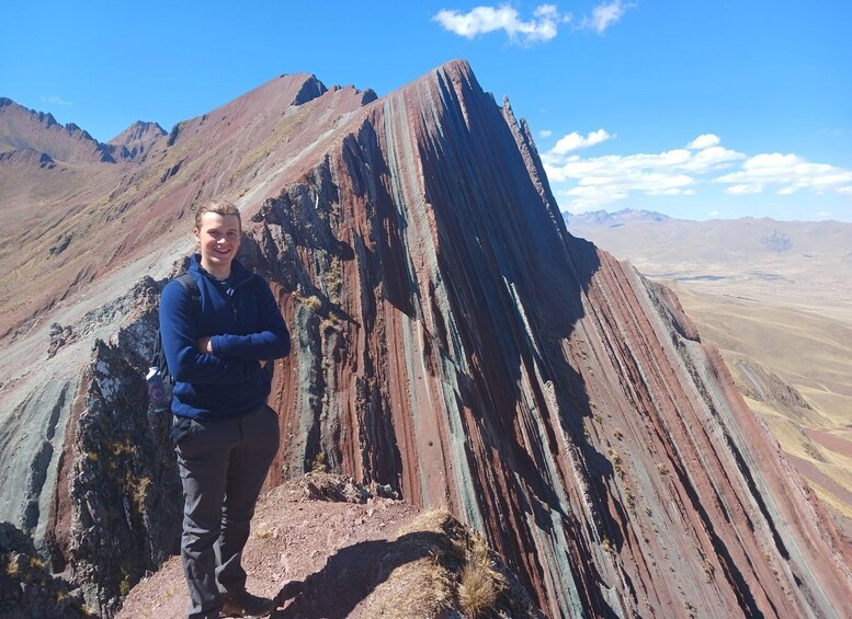 A person standing in front of a large, striped rock formation. 1