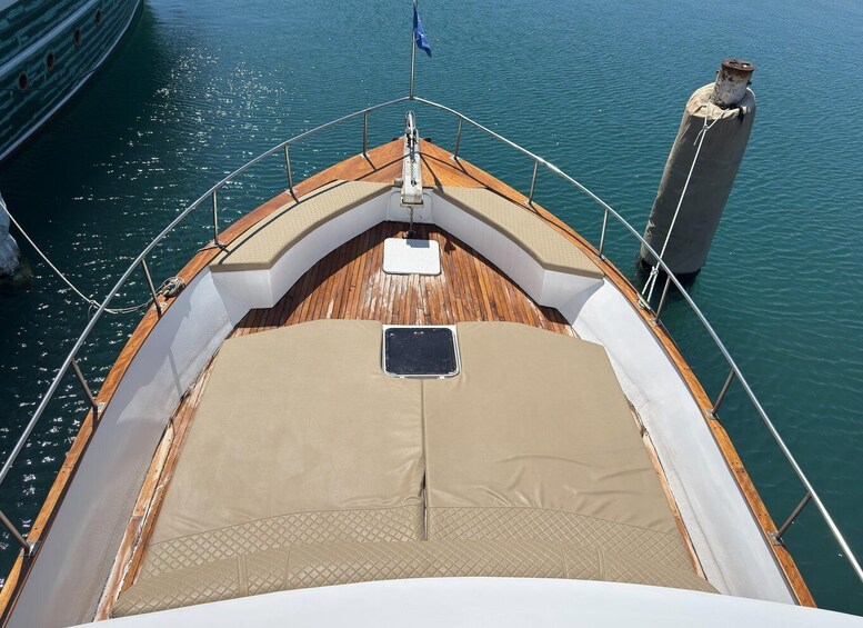 A boat's deck with a central seating area, a flag, and a buoy in the background. 4
