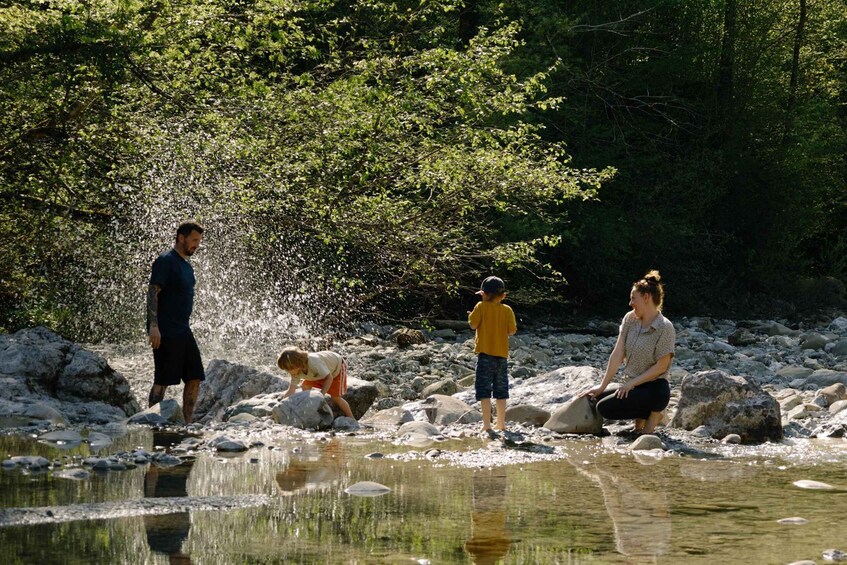 A family by a river with rocks and trees. 3