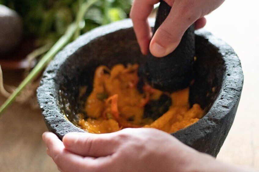 A person using a mortar and pestle to grind ingredients. 5