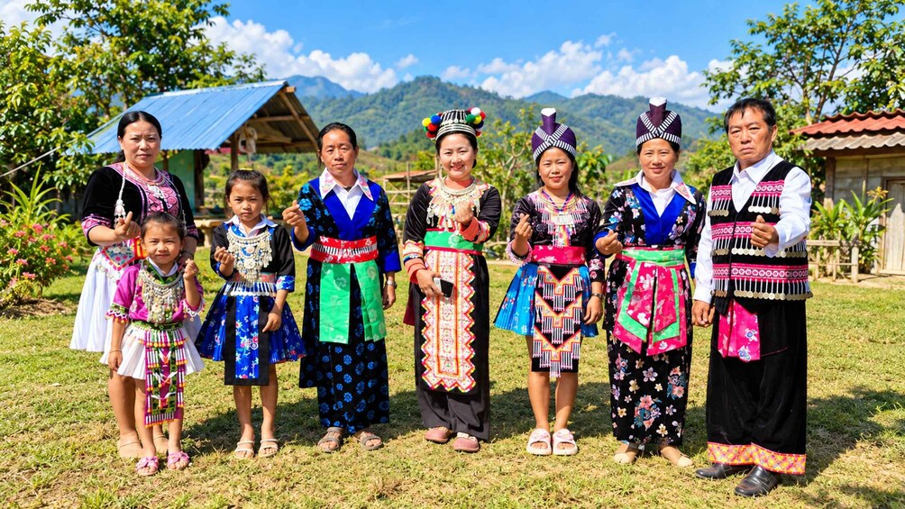 A group of people in traditional attire standing on grass with a mountain backdrop. 1