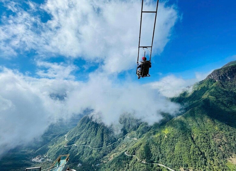 A cable car suspended over a mountainous landscape with lush greenery and winding roads below. 3